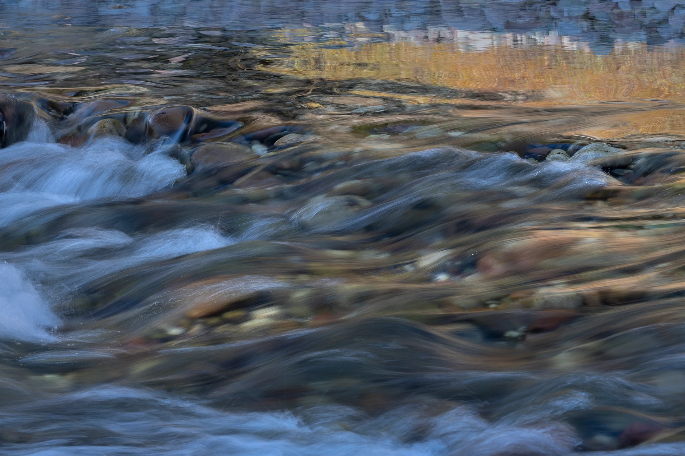 A waterfall flows over rocks in a mountain landscape.