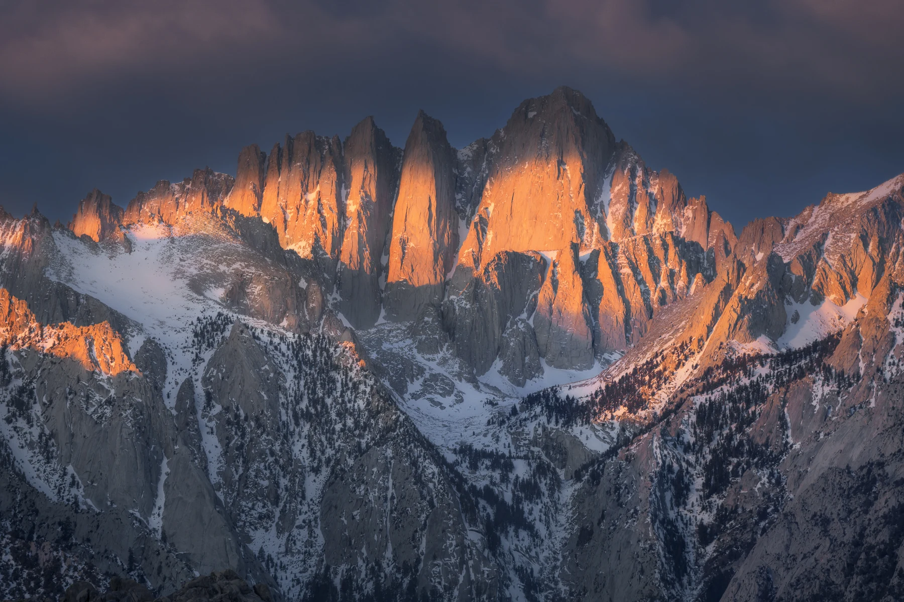 Fiery evening light illuminates jagged Sierra peaks above granite ridges.