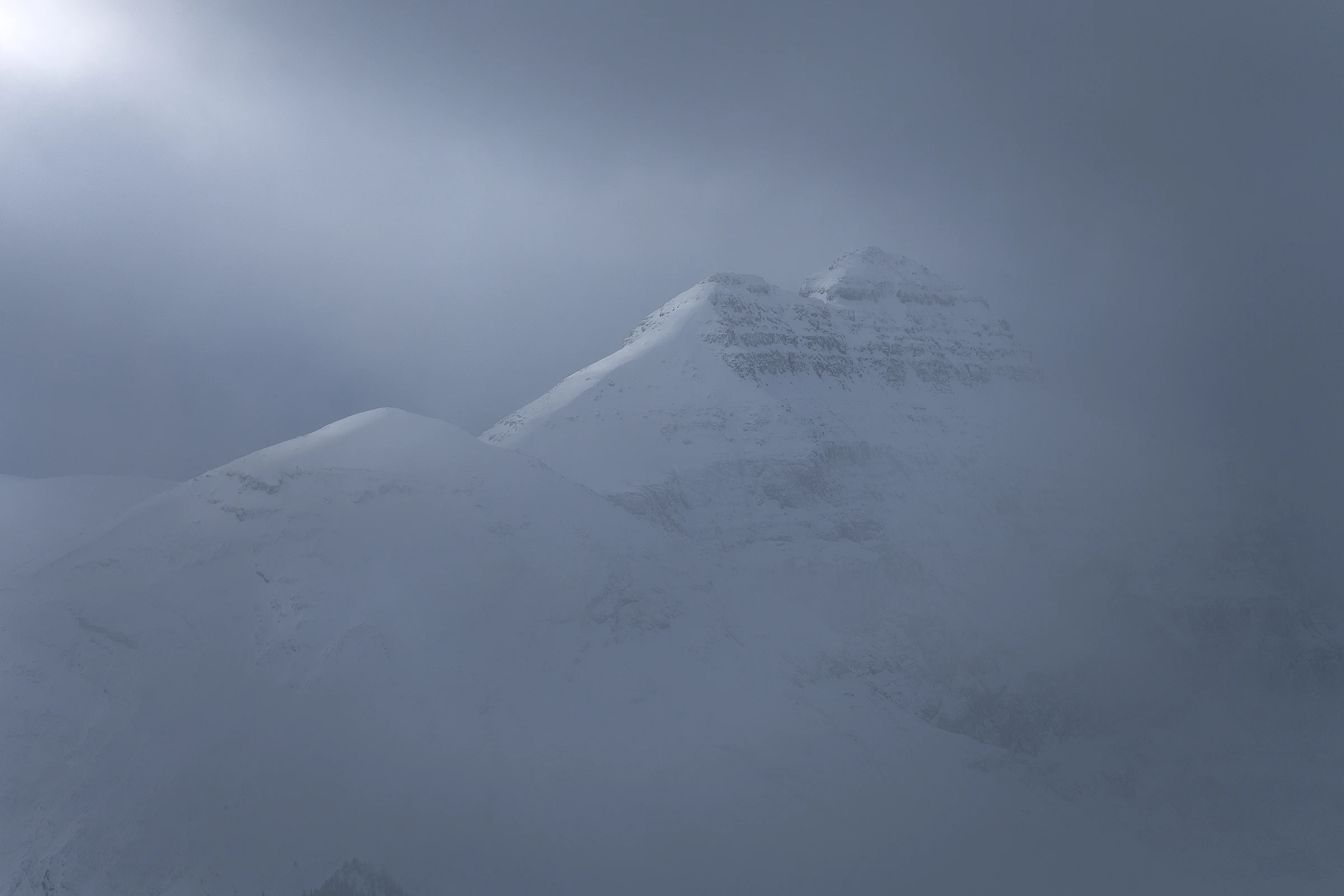 Snowy mountain peak partly hidden in gray mist.