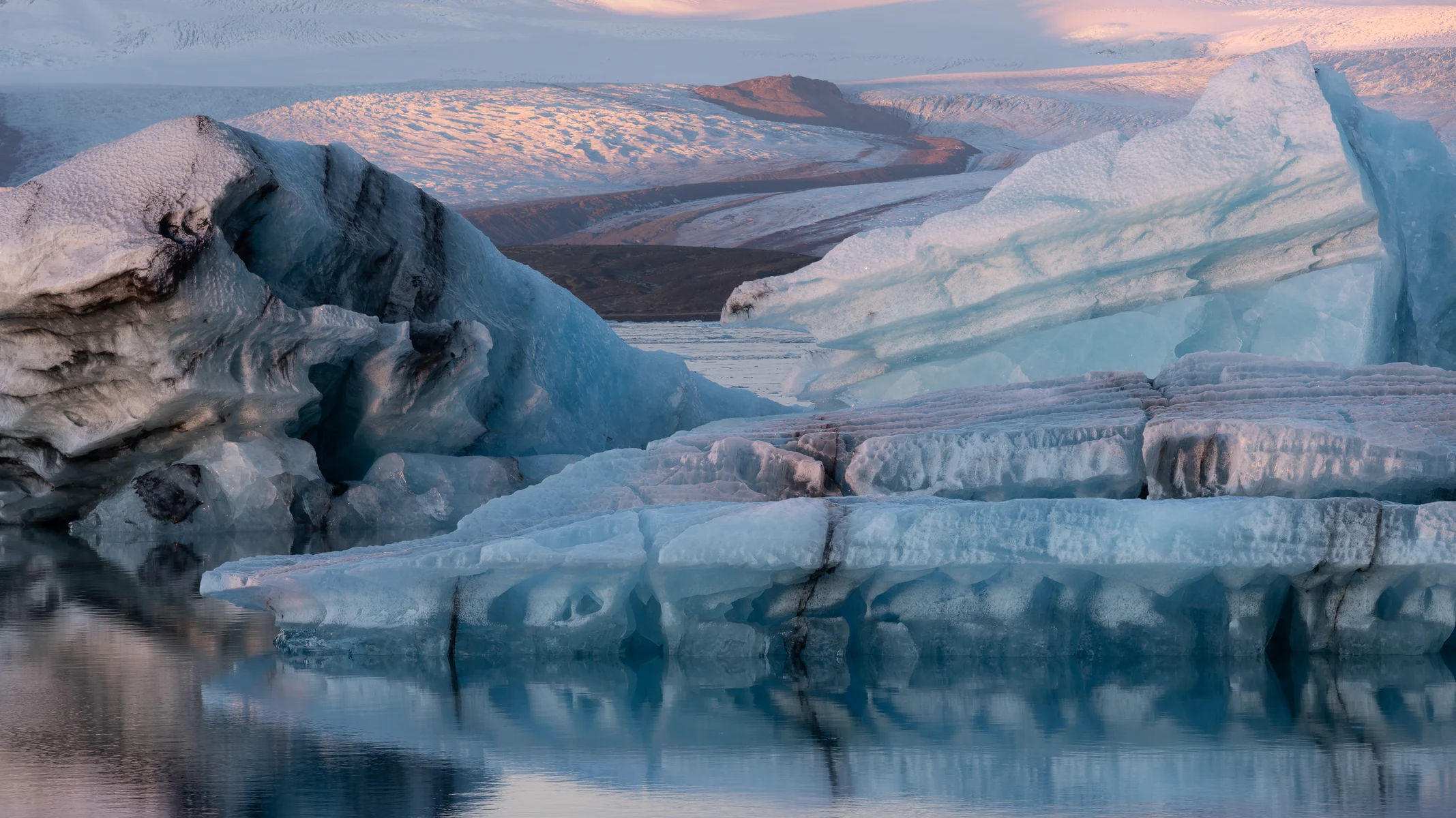 Glacier ice reflected in calm blue water.