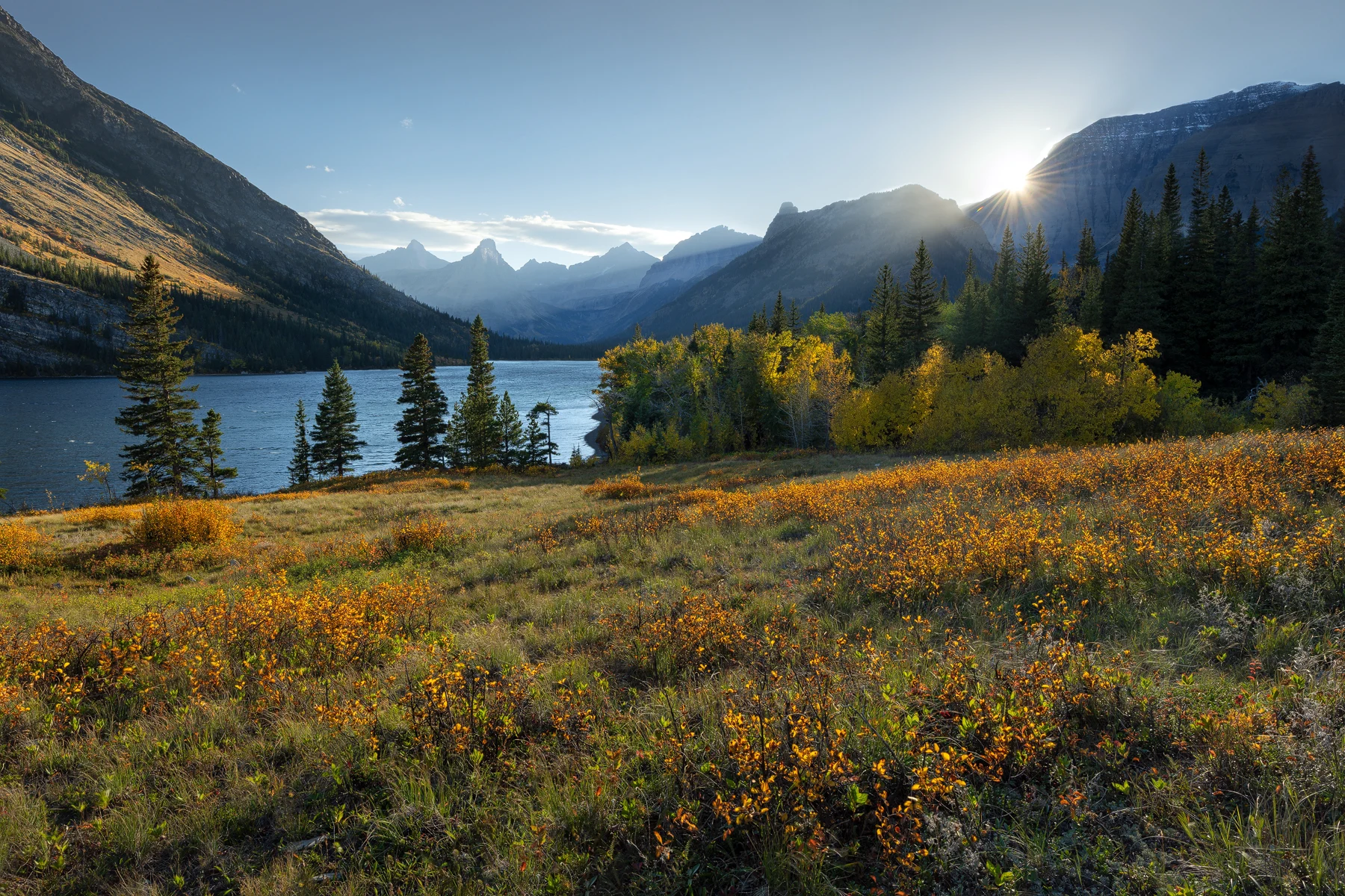 Cosley Lake beneath Mount Cleveland and a cloud-filled evening sky in Glacier National Park