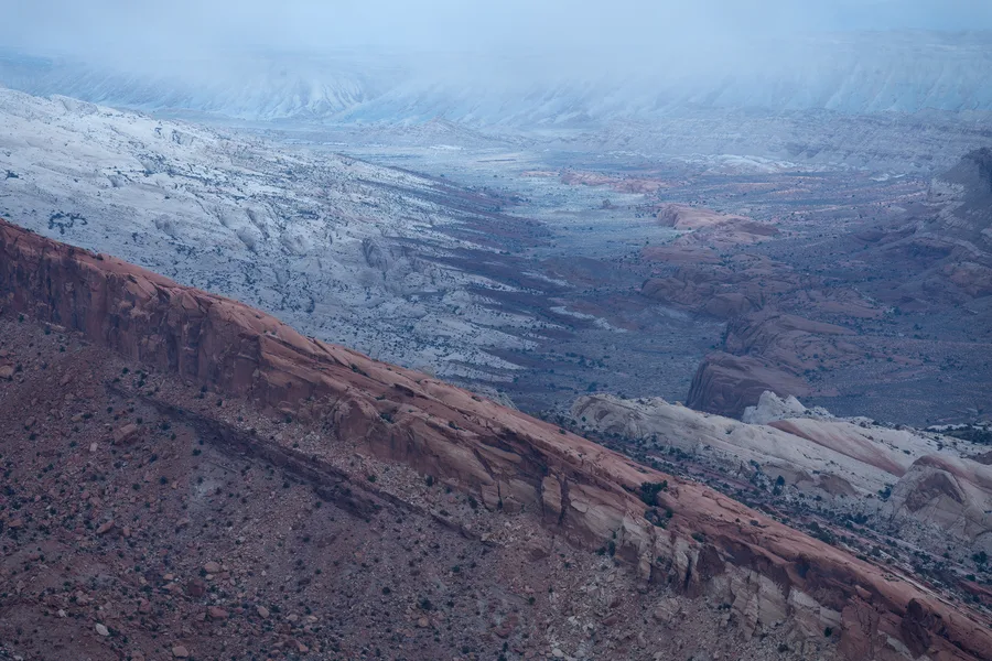 Layered desert canyons fading into blue and purple haze.