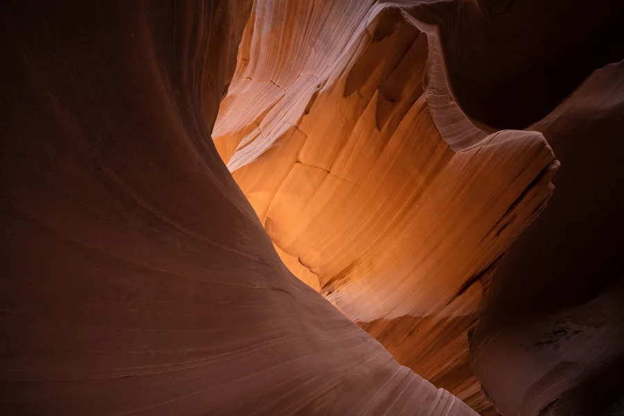 Golden light glowing through smooth orange slot canyon walls.