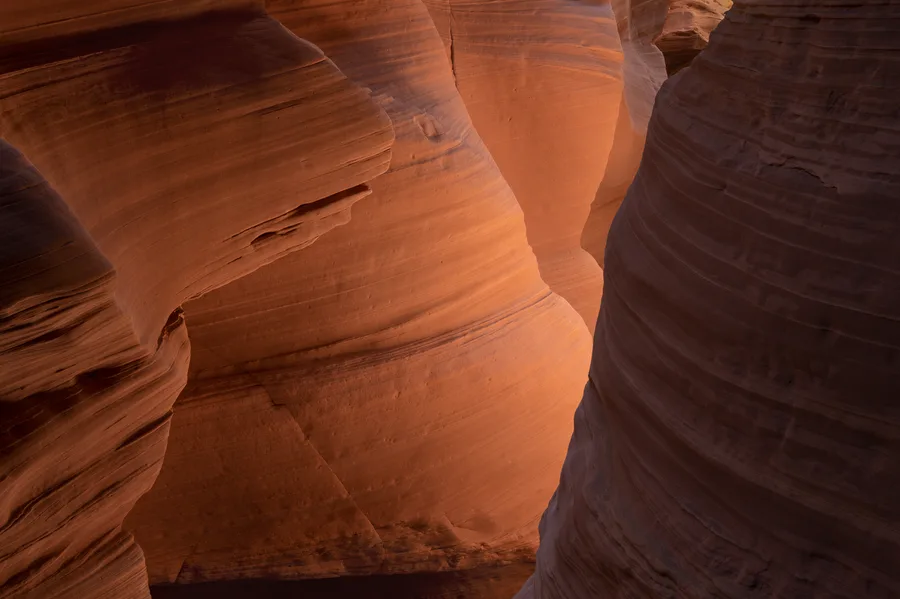 Soft golden light spilling through curved sandstone canyon walls.