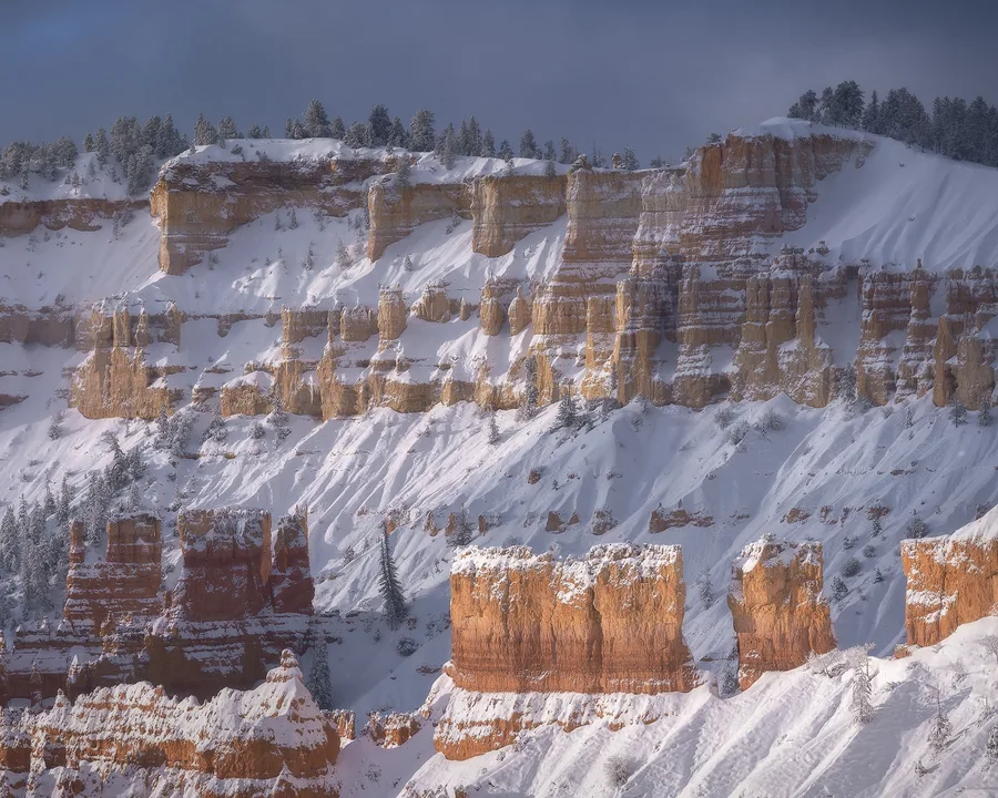 Snow-dusted sandstone cliffs in a canyon.