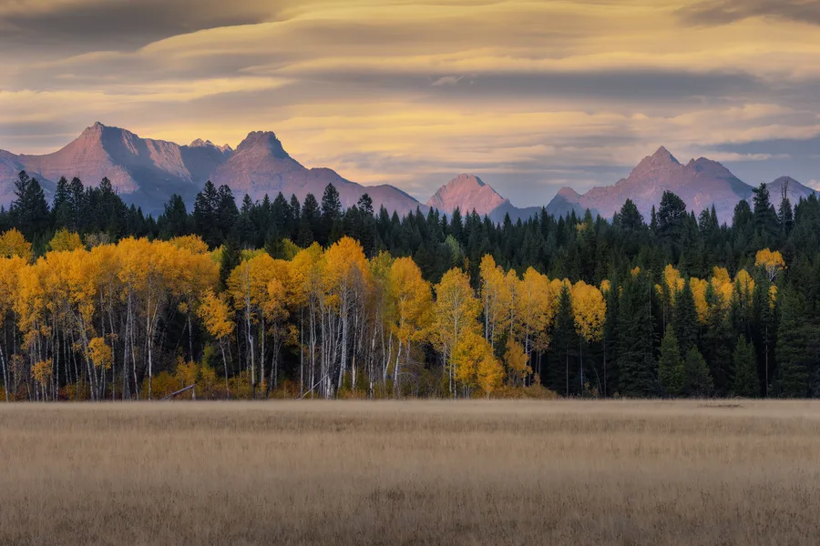 Sunlit mountains rise beneath a cloudy sky.