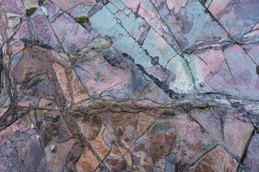 Colorful mineral patterns form an abstract detail in fractured rock.