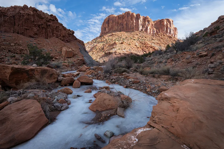 Creek flowing through orange desert canyon walls.