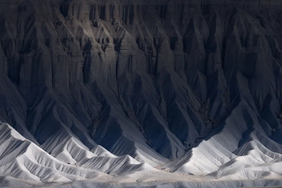 Dark gray badlands ridges with bright white eroded slopes below.