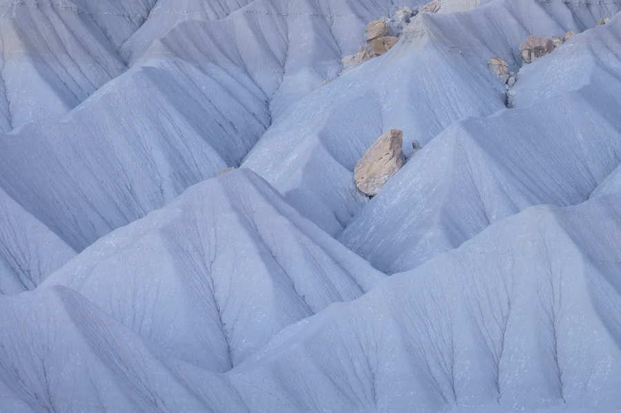 Pale blue badlands ridges forming soft abstract patterns.