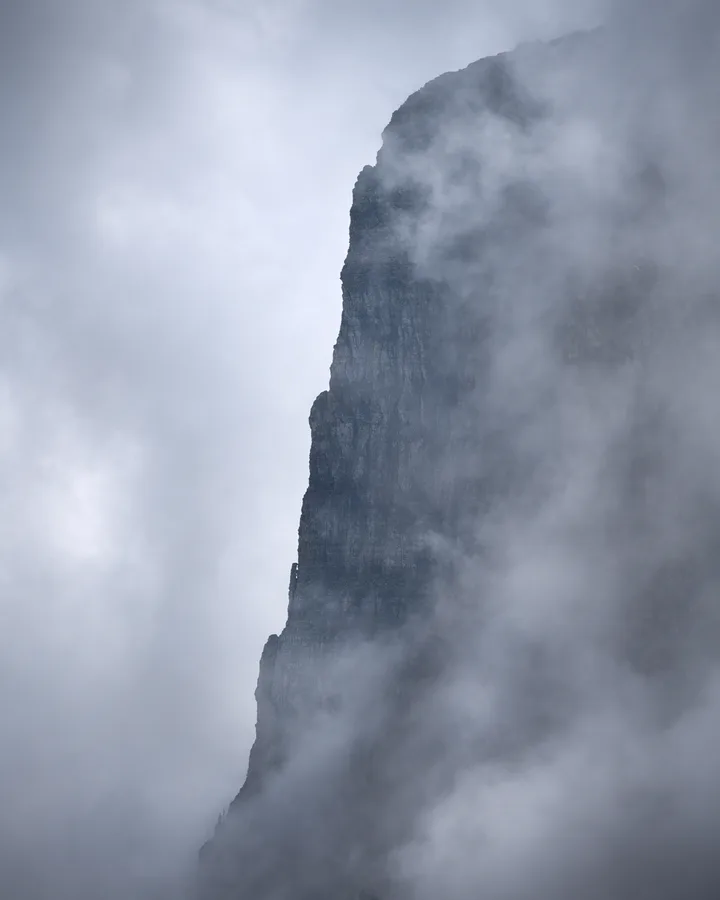 A towering column of cloud rises into a pale blue sky.