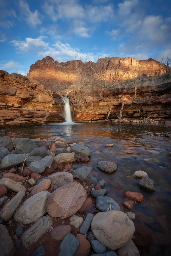 A waterfall flows over rocks in a mountain landscape.