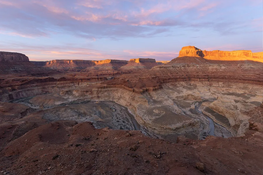 Open desert badlands and cliffs under a pastel sunset sky.