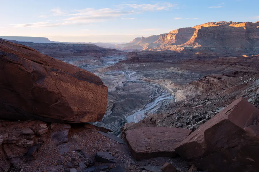 Wide canyon view with a winding river and warm red rock foreground.