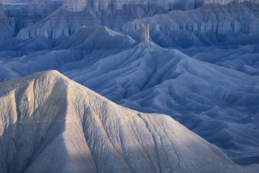 Blue and white badlands ridges receding through soft light.