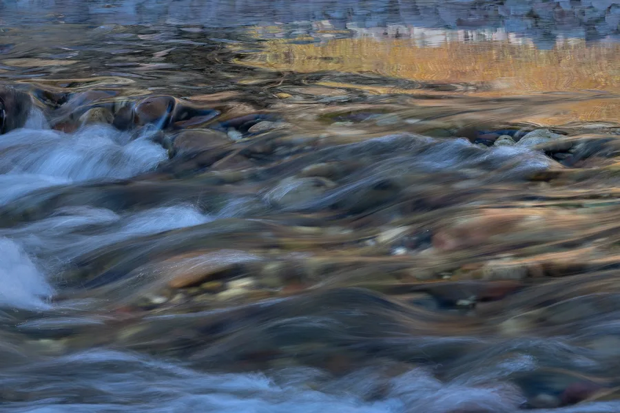 A waterfall flows over rocks in a mountain landscape.