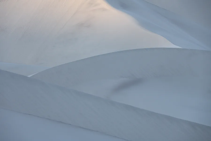 Eureka Sand dunes in Death Valley move and sway with soft light penetrating the faces of dunes.
