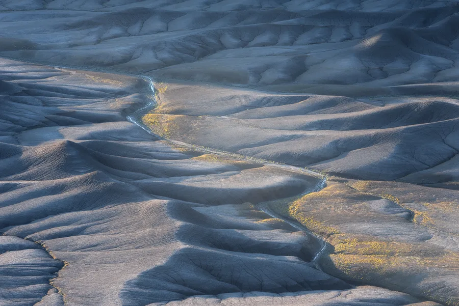 Blue-gray badlands ridges with pale golden erosion lines.