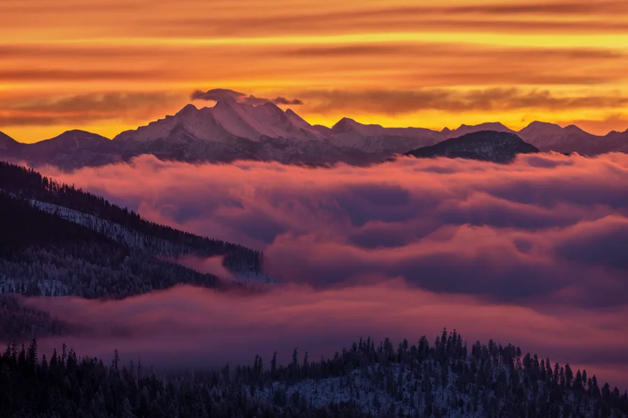 Red-orange sunset above mountains and a sea of clouds.