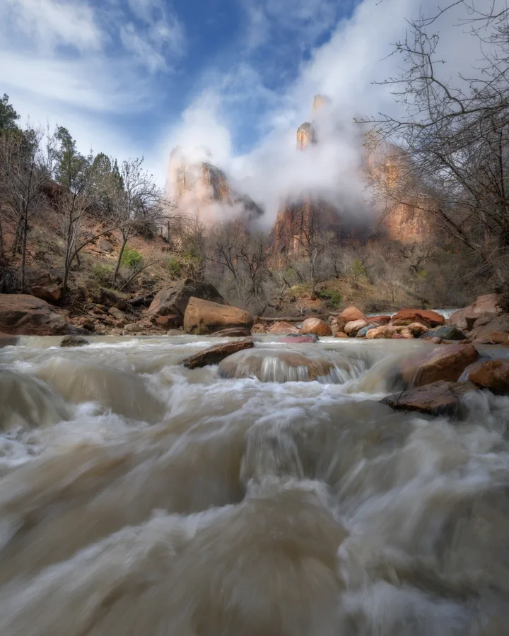 A powerful mountain river rushes between rocks and autumn trees.