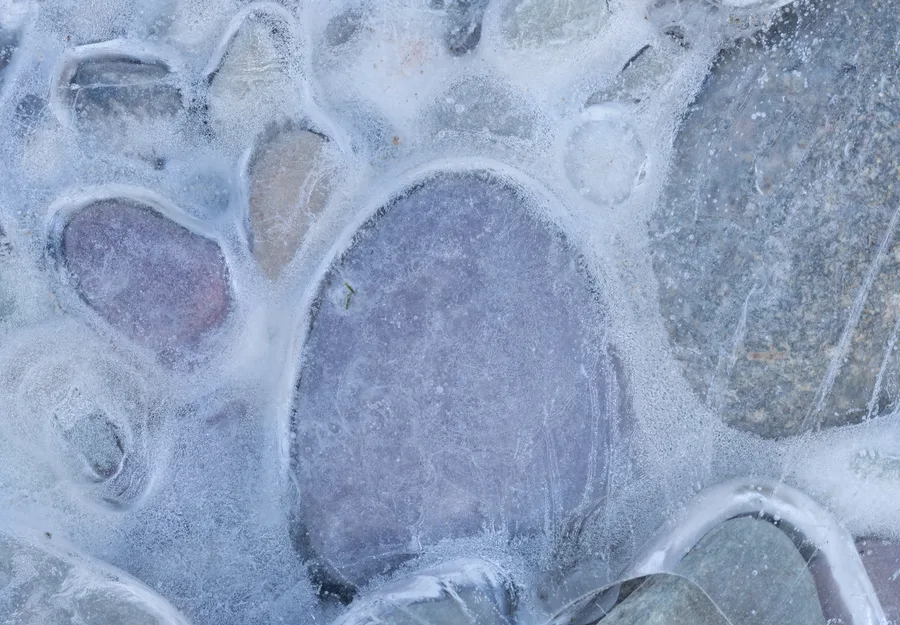 Rounded stones appear beneath a translucent layer of ice.