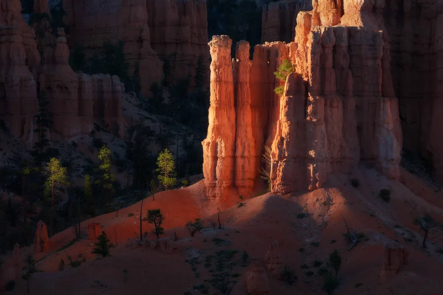 Orange hoodoos and desert cliffs in deep shadow and sunlight.