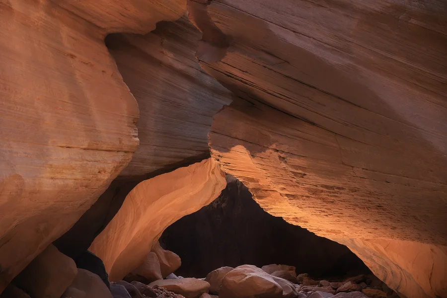 Low arch of warm sandstone inside a shadowed slot canyon.