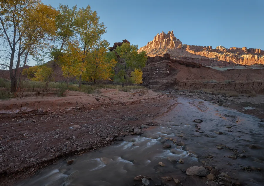 Desert creek and cottonwood trees below Golden Castle cliffs.