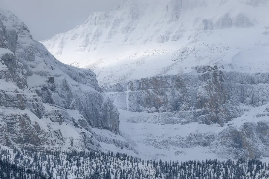 Snow and ice layers across a distant winter mountain wall.