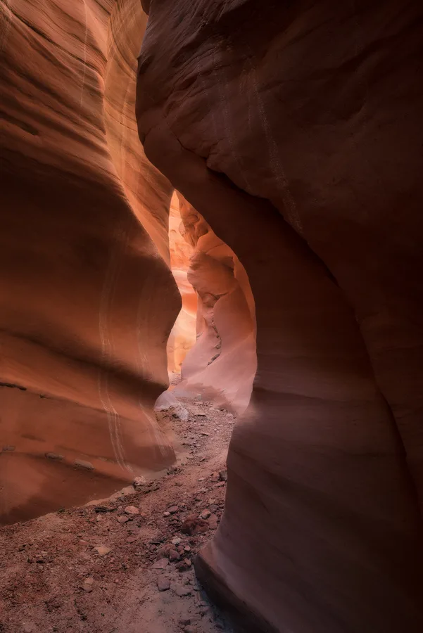 Vertical orange slot canyon passage with hypnotic sandstone curves.