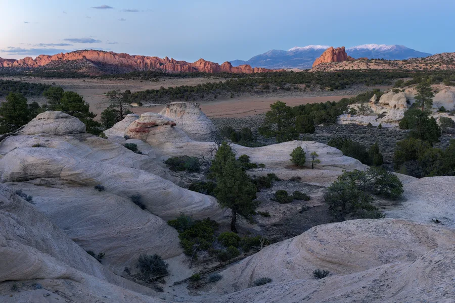 Warm light crosses sandstone cliffs in a canyon beneath a cloudy sky.