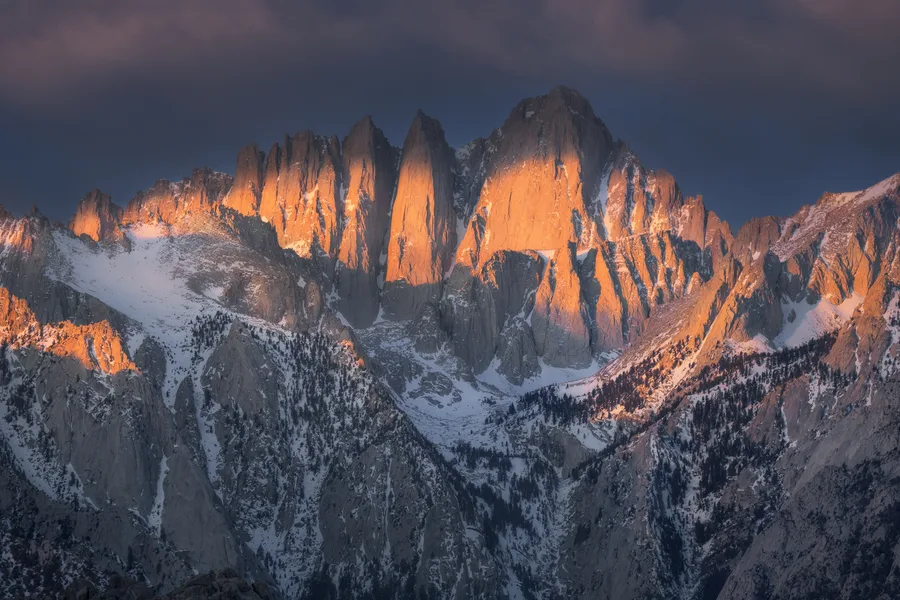 Fiery evening light illuminates jagged Sierra peaks above granite ridges.