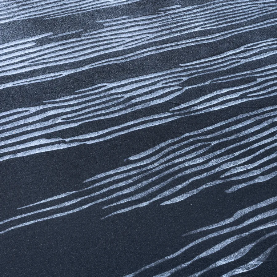 White wind-carved lines across black Iceland sand.
