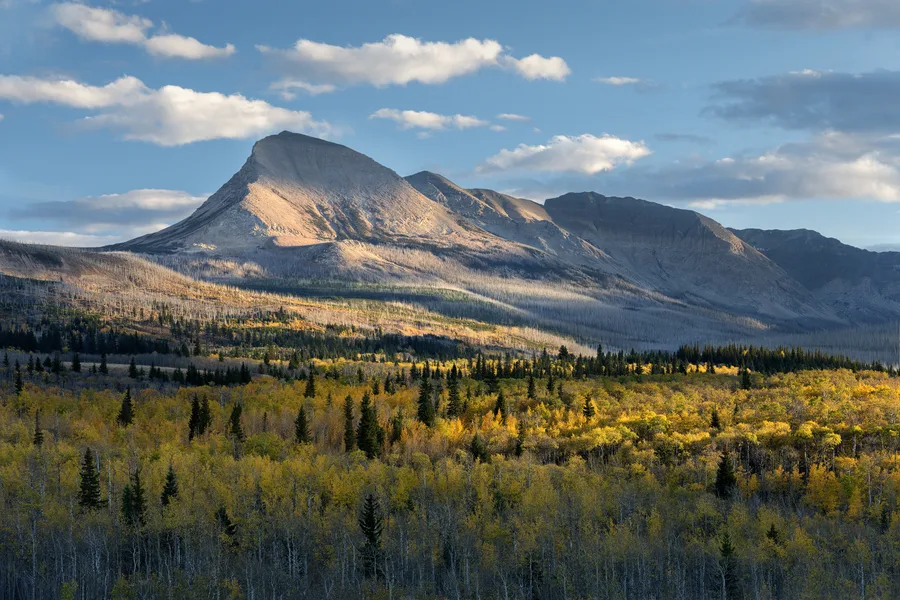 Sunlit mountains rise beneath a cloudy sky.