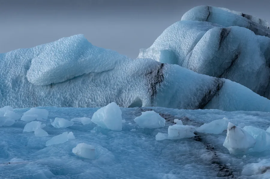 Blue icebergs and quiet water in a misty glacier lagoon.