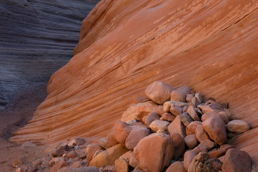 Rounded sandstone rocks gathered below orange canyon walls.