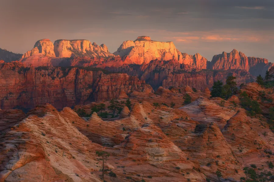 Red sandstone cliffs glowing beneath dark storm clouds.